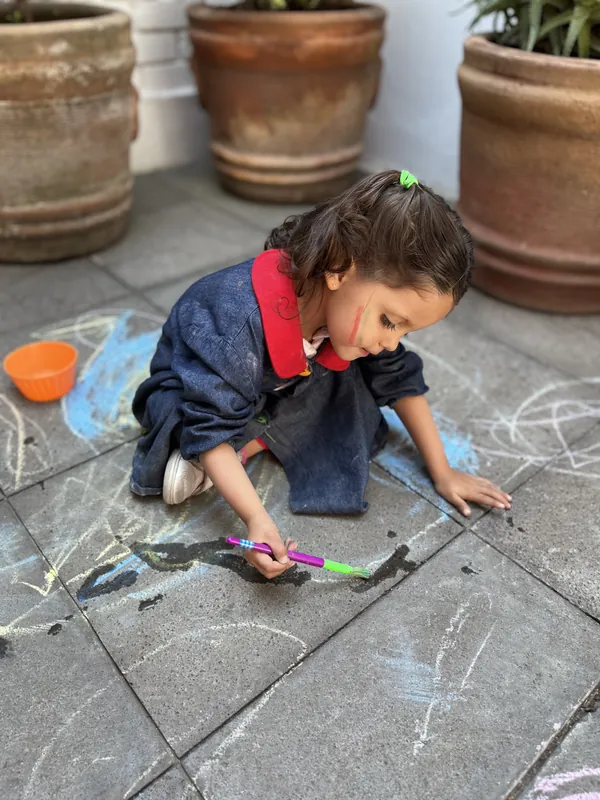Niña dibujando con gises en el patio