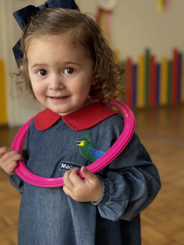 Niña sonriendo con un aro rosa en el cuello